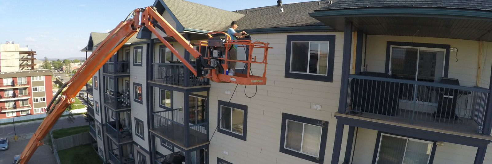 Employee in lift power washing 4th floor of building